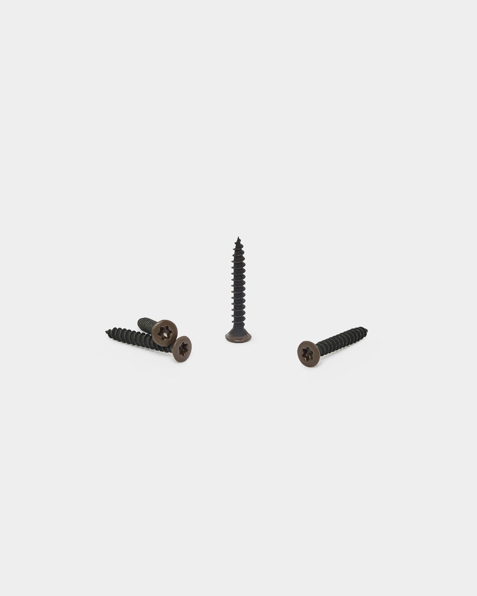 Tres tornillos WoodUpp bronzed brown, uno en vertical y dos tumbados, diseñados para fijar el soporte de fieltro a los paneles acústicos Akupanel. Pack de 100.